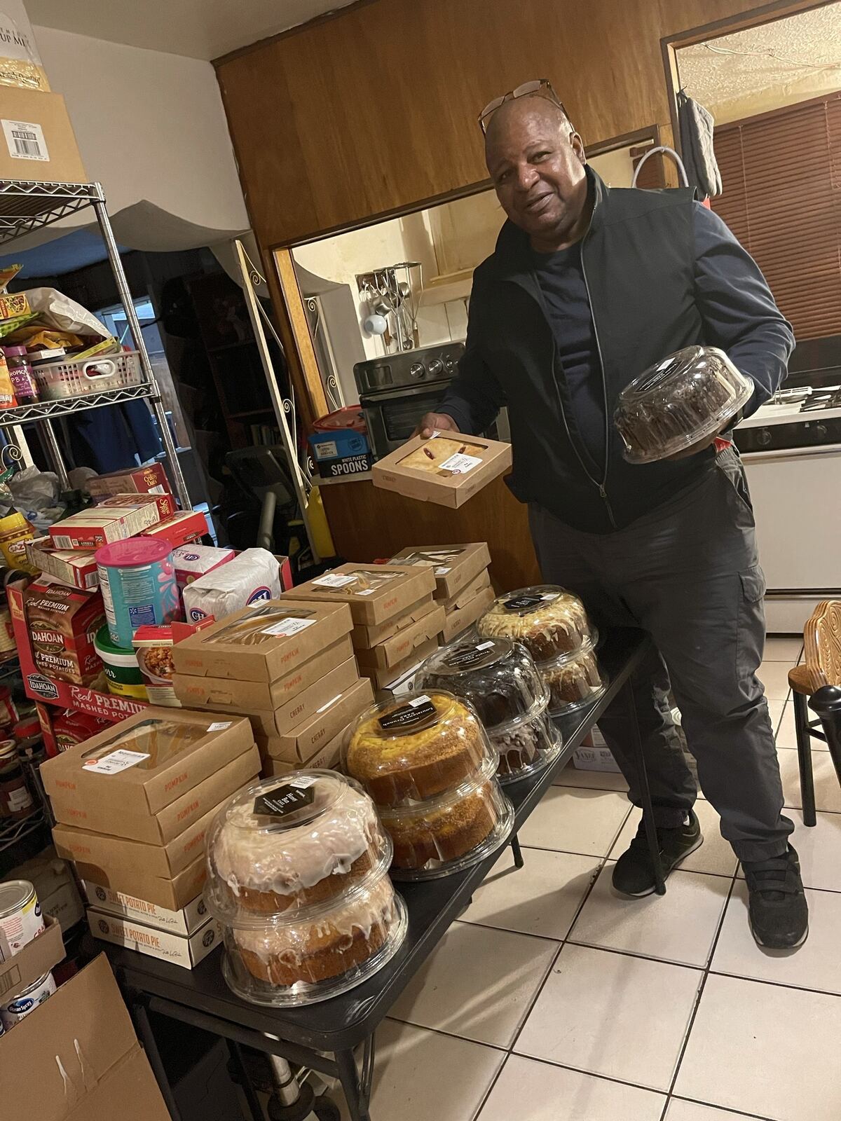 Pastor James Peoples standing beside tables stacked with donated food before an outreach.