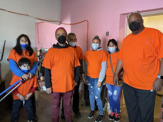 Volunteers in matching orange Casa Rescate shirts standing together inside the recovery home.